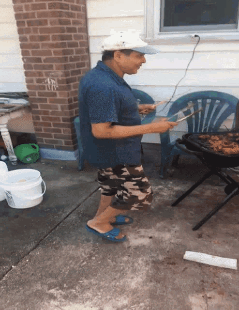 a man standing in front of a grill with a bucket that says ' a ' on it