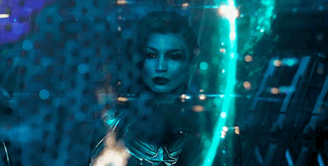 a woman in a superhero costume is surrounded by blue lights