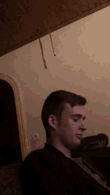 a man is sitting on a couch with a rope hanging from the ceiling