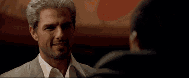 a man in a suit is talking to another man with the word great behind him