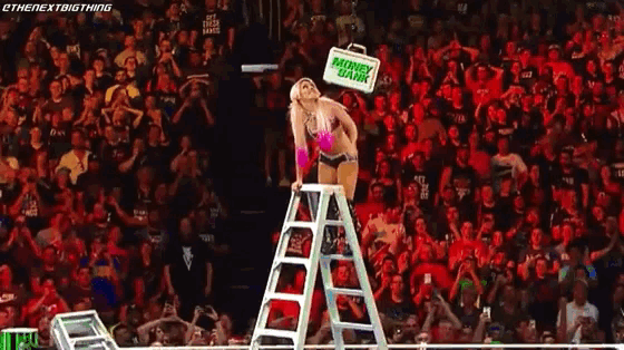 a woman is standing on a ladder in front of a crowd holding a sign that says mothers day .