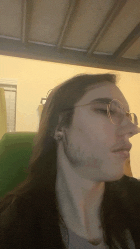 a man with long hair and glasses is sitting in a chair