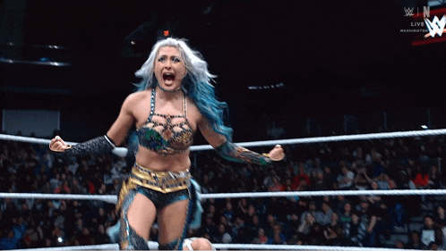 a woman with blue hair is in a wrestling ring with a w logo