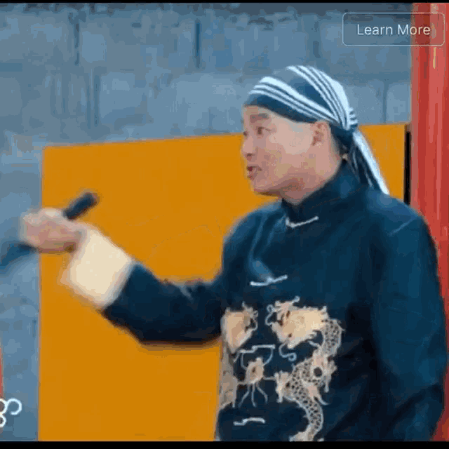 a man with a bandana on his head is holding a microphone and pointing at something .