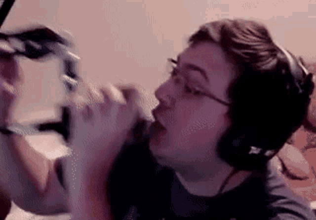 a man wearing headphones is singing into a microphone while playing a video game .