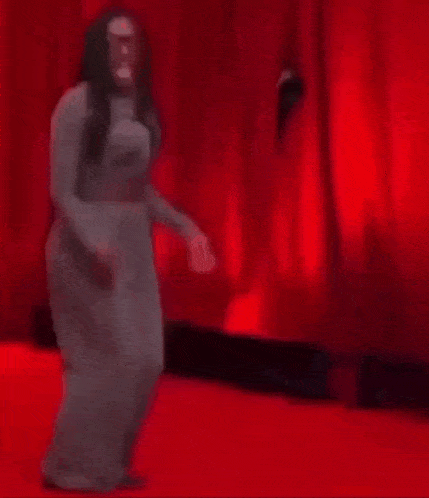 a person is laying on the ground in front of a red curtain .