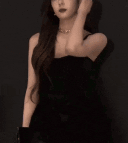 a woman in a black dress is standing in a dark room .