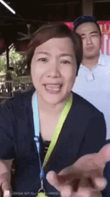 a woman with a lanyard around her neck is talking to a man behind her