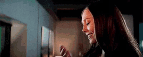 a woman with long hair is smiling in a living room while looking at something .