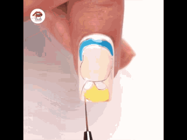 a close up of a person 's nails being painted with a yellow and blue design .