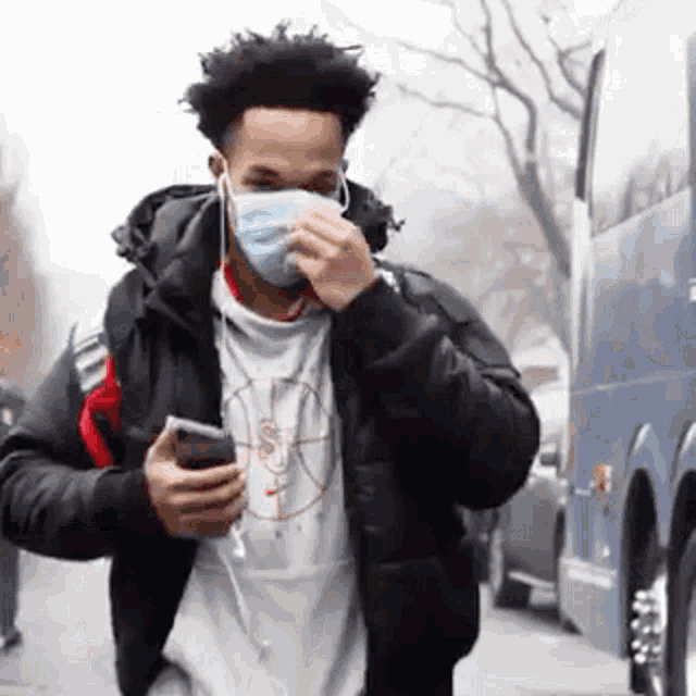 a man wearing a mask is holding a cell phone .