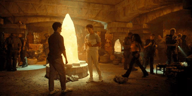 a group of people standing in a dark room with a large glowing object in the center