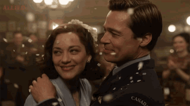 a man in a canadian uniform is hugging a woman in a blue dress