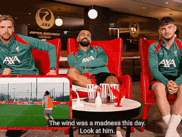a man in a green aya shirt sits next to another man in a red chair