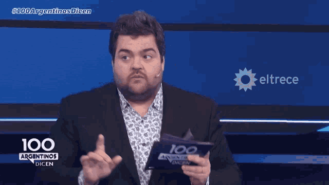 a man in a suit is holding a piece of paper that says 100 argentinas dien
