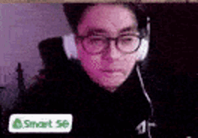 a man wearing glasses and headphones is sitting in front of a laptop computer .