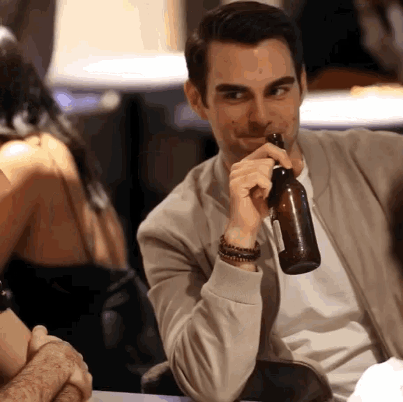 a man is drinking from a brown bottle with a label that says ' amber ale ' on it