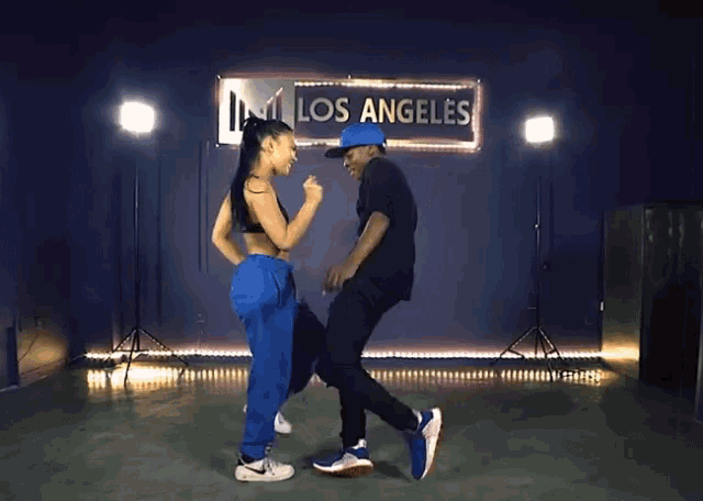 a man and a woman dance in front of a sign that says los angeles