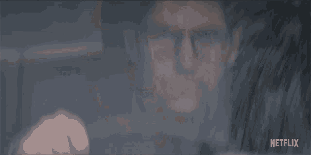 a blurred image of a man with glasses and a netflix logo in the corner