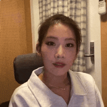 a woman wearing a white shirt and a necklace looks at the camera