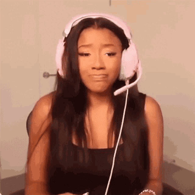 a woman wearing pink headphones and a headset is making a funny face .