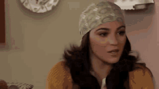 a woman wearing a headband and a yellow sweater is sitting in front of a lamp .