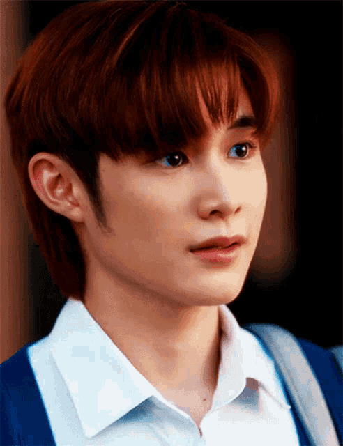 a close up of a person 's face with a white shirt and a blue cardigan