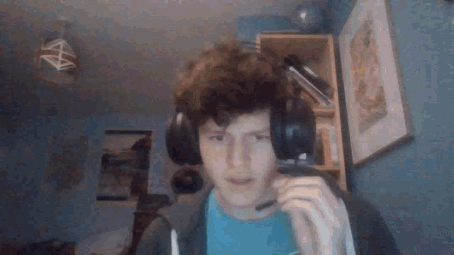 a young man wearing headphones and a microphone looks at the camera