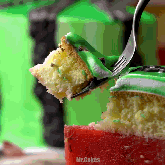 a slice of cake with green frosting is being eaten with a fork by mr cakes