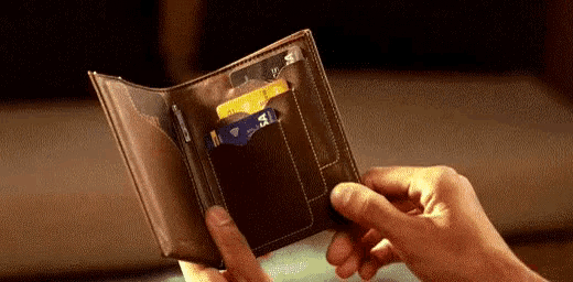 a person is holding a brown wallet with a lot of cards in it .