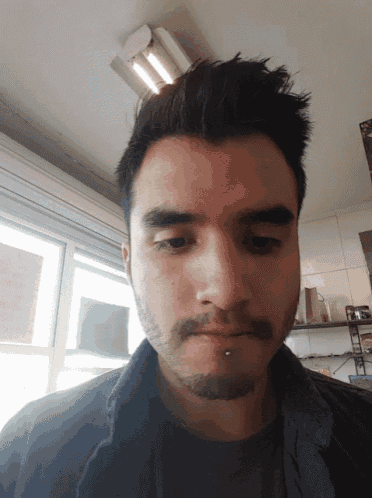 a man with a beard and a nose piercing looks at the camera