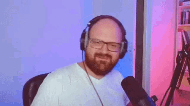 a man with a beard and glasses is wearing headphones and singing into a microphone .