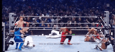 a group of wrestlers are fighting in a wrestling ring with a crowd watching .