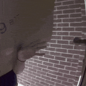 a person is standing in front of a brick wall with a door open