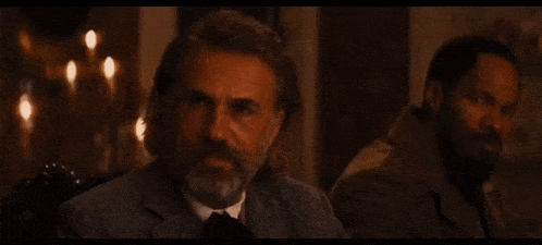 a man with long hair and a beard sits next to another man with a beard