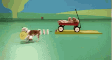 a red wagon filled with puppies is on a green surface .
