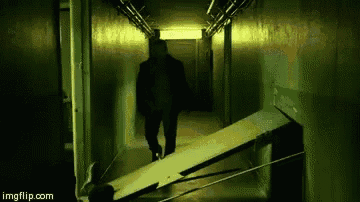 a man is walking down a dark hallway with a ramp in the corner .