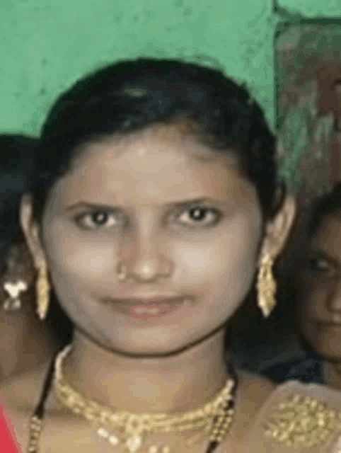 a woman wearing a gold necklace and earrings is smiling .