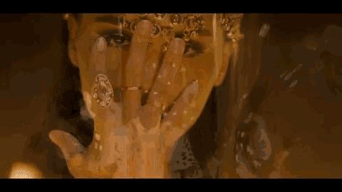 a close up of a woman covering her face with her hand and wearing rings .