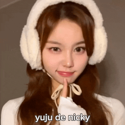 a girl wearing ear muffs and a white hat is making a peace sign .