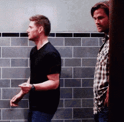 two men are standing next to each other in a bathroom .