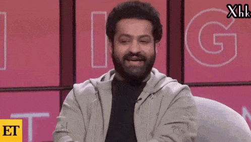 a man with a beard is smiling in front of a sign that says et