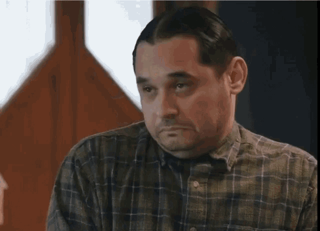 a man wearing a plaid shirt is looking at something