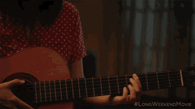 a woman playing a guitar with the longweekendmovie written below her