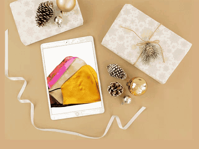 a tablet with a picture of a purse on the screen surrounded by christmas decorations