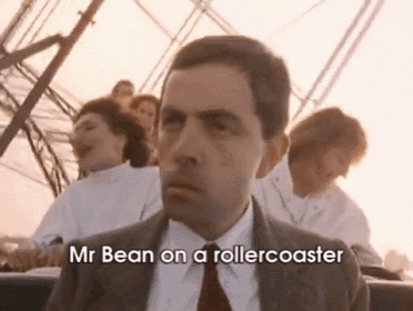 a man in a suit and tie is sitting on a roller coaster and says mr bean on a rollercoaster