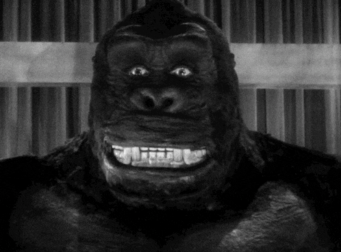 a black and white photo of a gorilla with big teeth