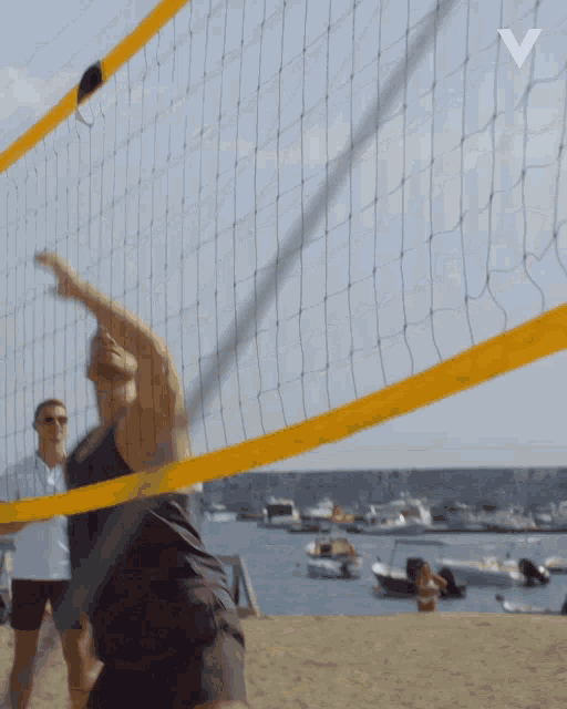 a man playing volleyball on a beach with the letter v in the upper right corner