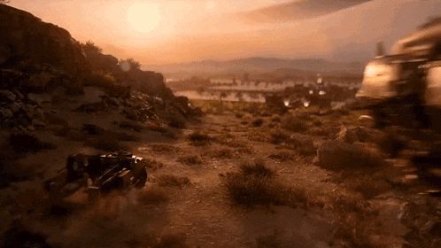 a motorcycle is driving down a dirt road in the desert at sunset