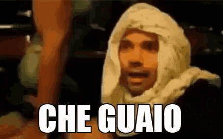 a man wearing a white scarf on his head is making a funny face and the words che guaio are written above him